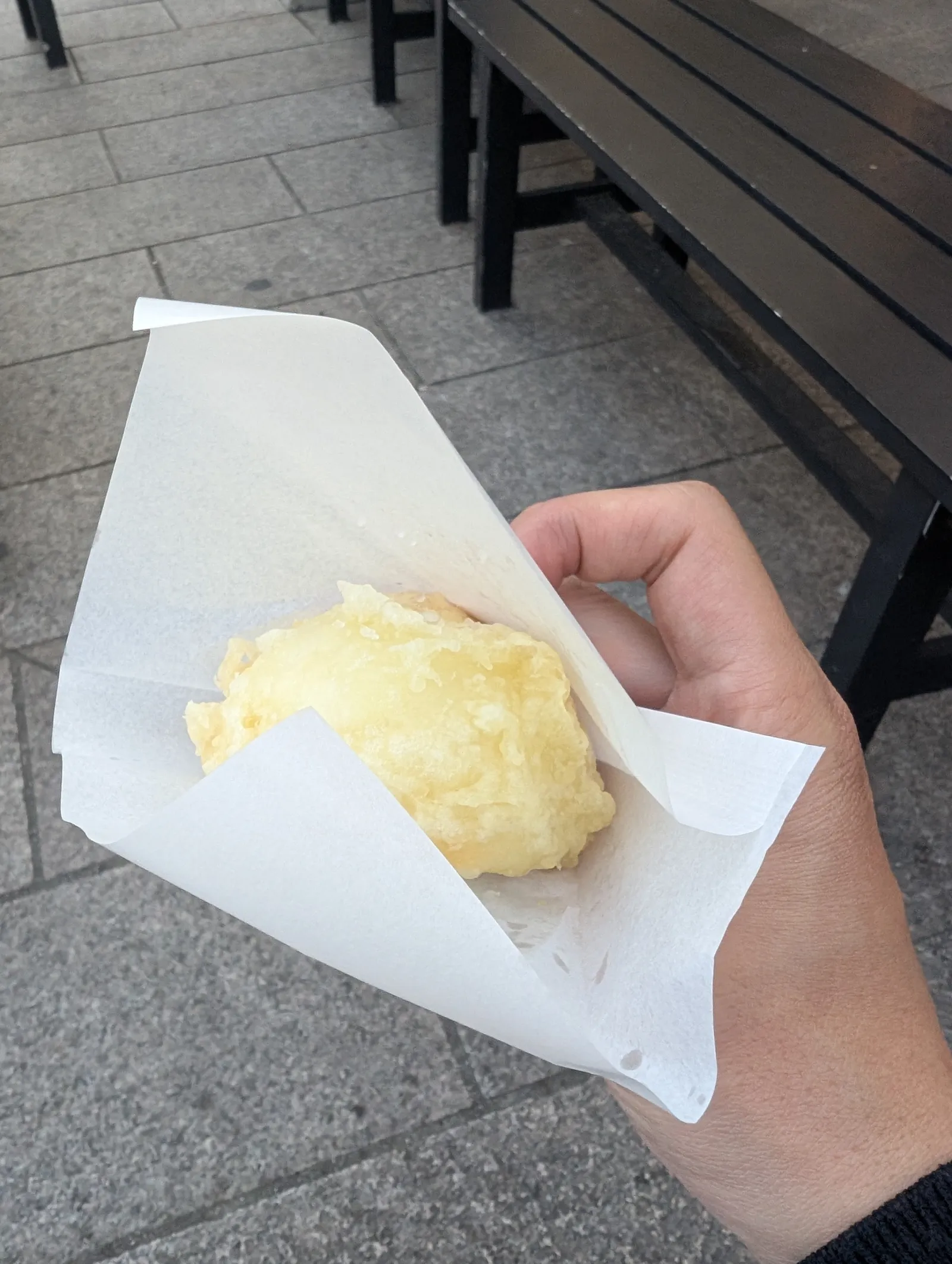 Mano sujetando un age-yuba manju recién frito, especialidad callejera de Nikko