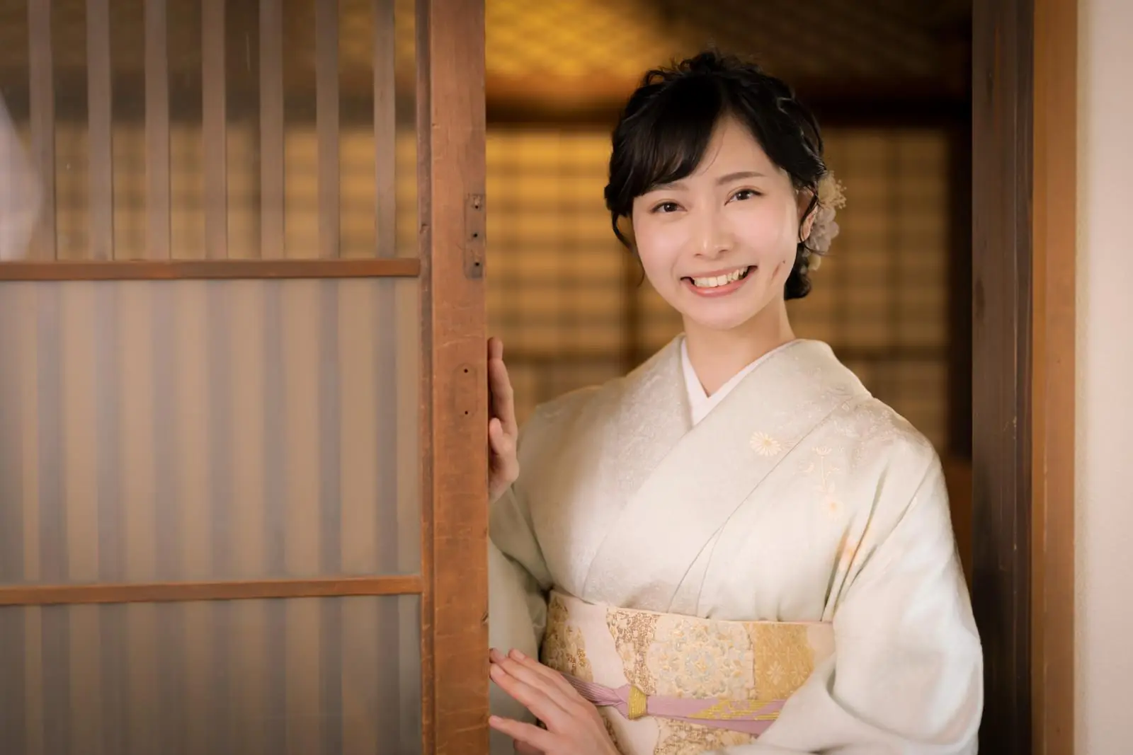 A nakai-san in elegant kimono greeting guests at a traditional Japanese ryokan entrance
