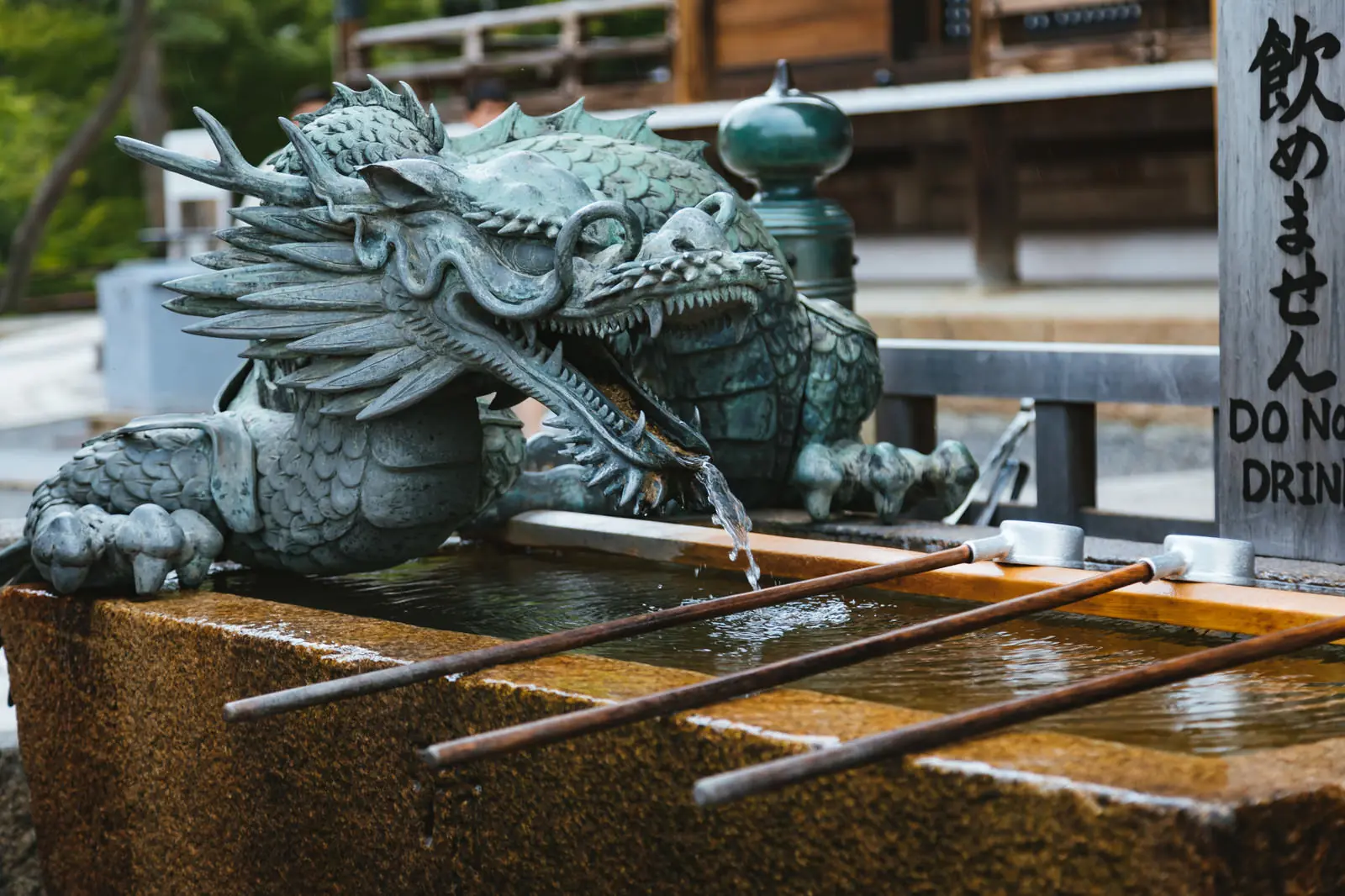 Dragon-shaped water spout at a chozuya purification fountain with bamboo ladles at a Japanese shrine