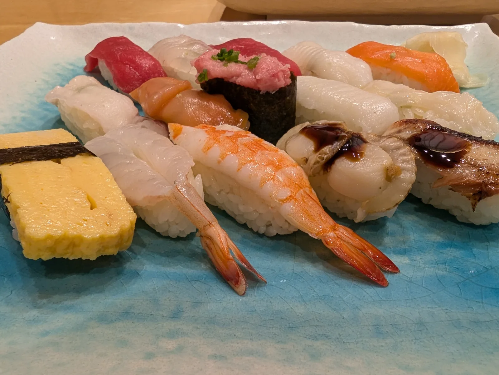 Assorted nigiri sushi platter — tamago, maguro, salmon, ebi, hotate, anago — at a Tokyo sushi counter