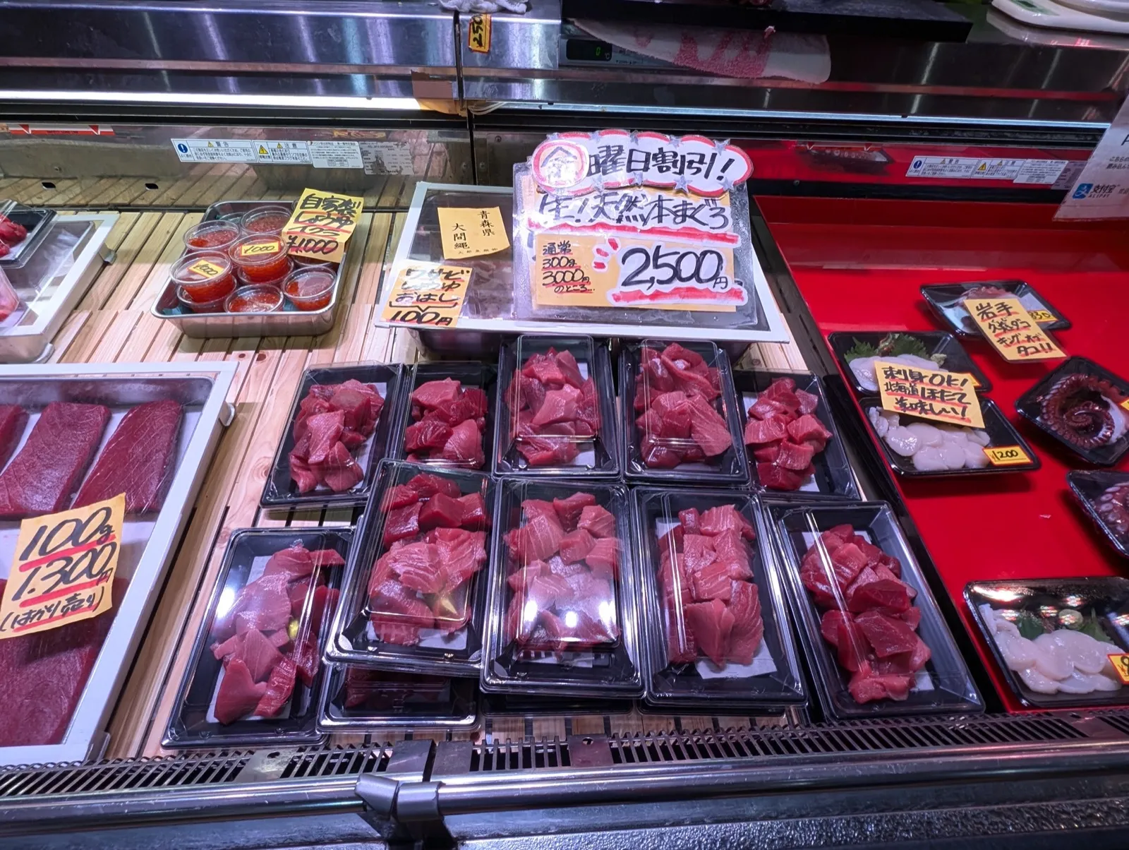 Fresh tuna cuts displayed at a Tsukiji market stall with handwritten price signs