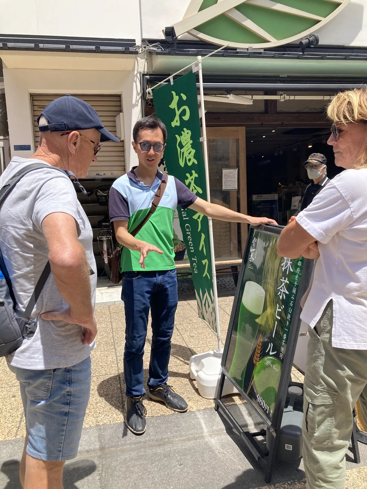 Manabu explicando el menú de una tienda tradicional de matcha a los visitantes en una calle lateral de Asakusa